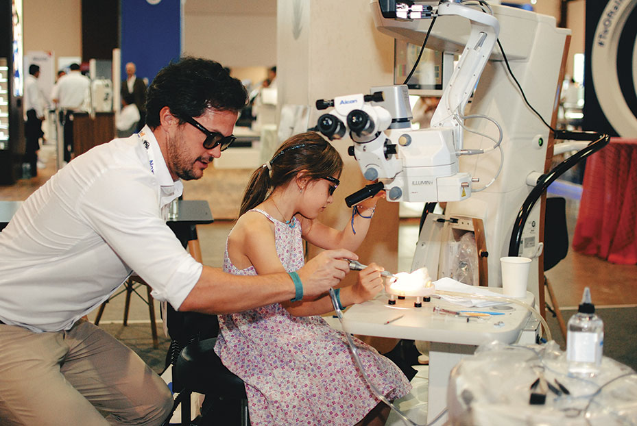 Hombre joven y niña practicando con equipo de oftalmología durante congreso mexicano de oftamología