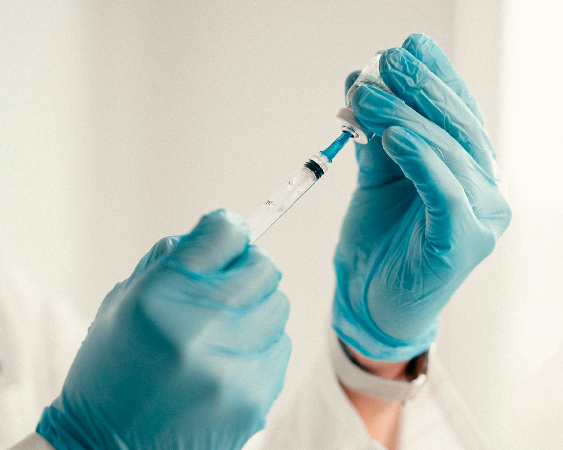 Manos de un médico con guantes de látex, preparando una inyección