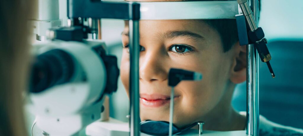 Niño recibiendo examen de la vista, diagnóstico distrofias hereditarias de retina, con máquina de oftalmología