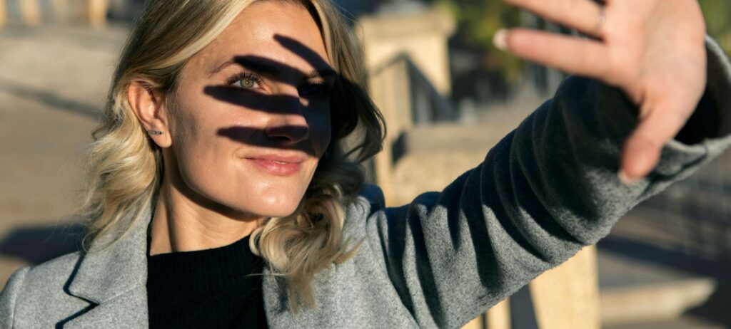 Mujer joven protegiendo sus ojos del sol usando su mano