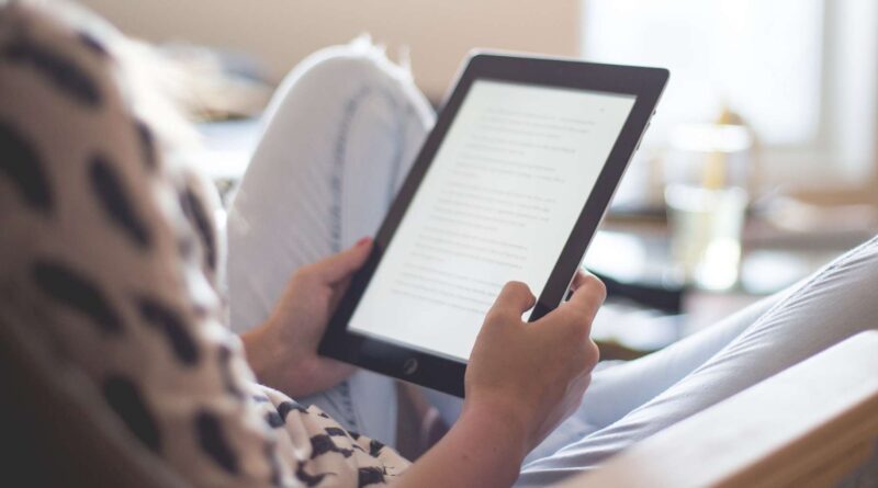 Persona sentada en una silla leyendo un texto en una tableta electrónica