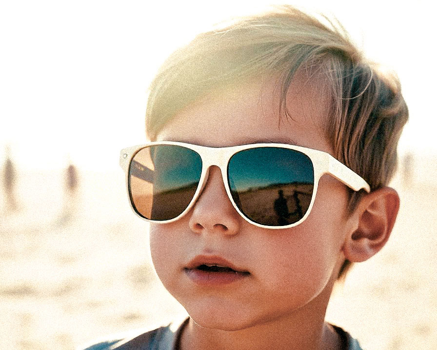 Fotografía de primer plano de un niño en la playa, usando lentes de sol