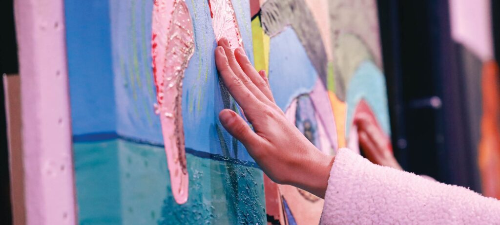 Mano de mujer tocando una obra de arte de color rosa, azul y verde