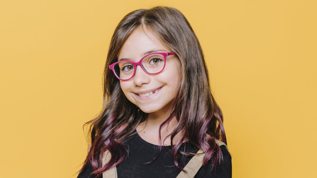 niña con lentes sonriendo a la cámara