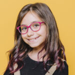 niña con lentes sonriendo a la cámara