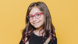 niña con lentes sonriendo a la cámara
