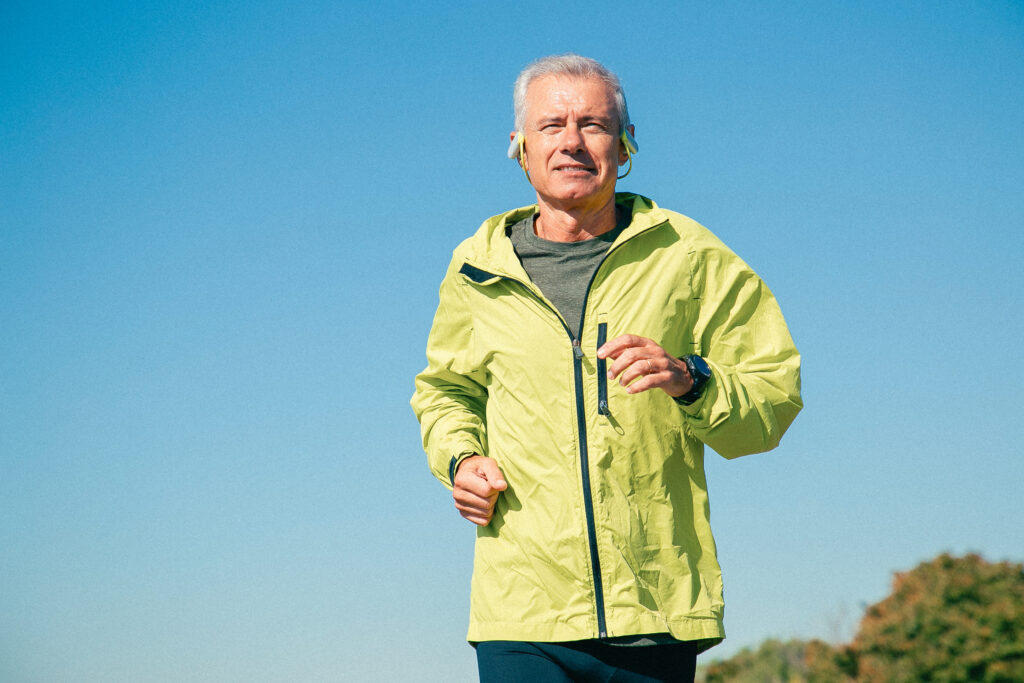 hombre mayor haciendo ejercicio para su salud visual, corriendo, usando ropa deportiva y con auriculares