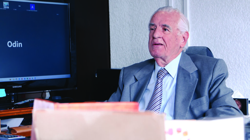 Dr. Rafael Sánchez Fontán, oftalmólogo, durante entrevista para revista Infoofta. Se observa sentado detrás de su escritorio. Se puede ver un monitor de computadora a lado y folders.