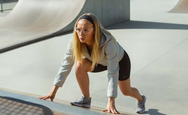 Mujer joven usando ropa deportiva, realizando actividad física luciendo concentrada, usando lentes para protección visual adecuados para un mejor rendimiento deportivo.