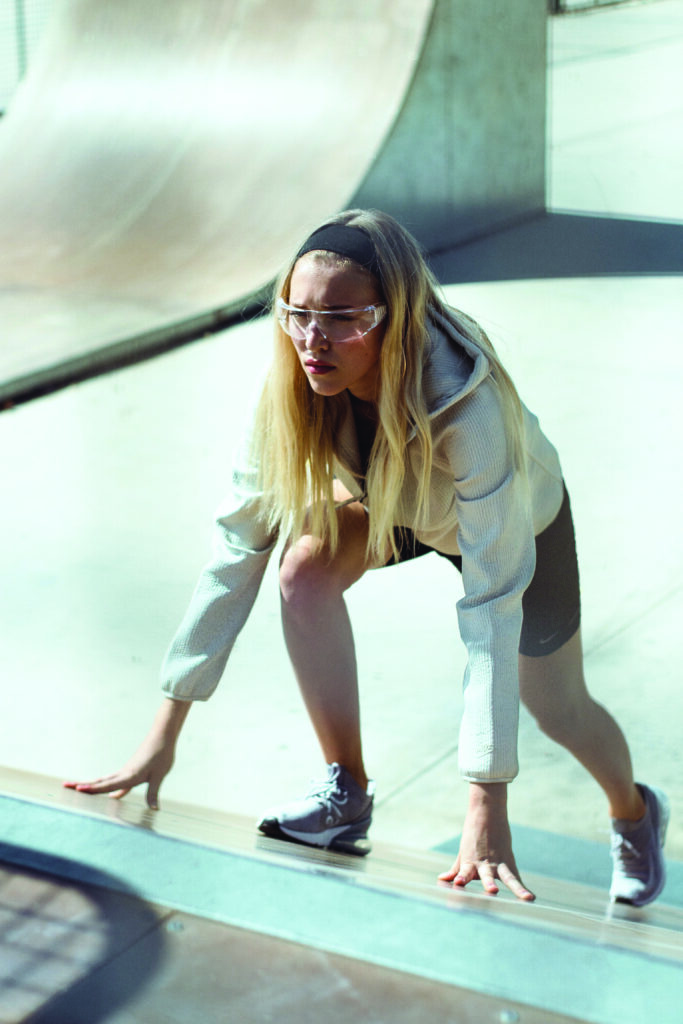 Mujer joven usando ropa deportiva, realizando actividad física luciendo concentrada, usando lentes para protección visual adecuados para un mejor rendimiento deportivo.