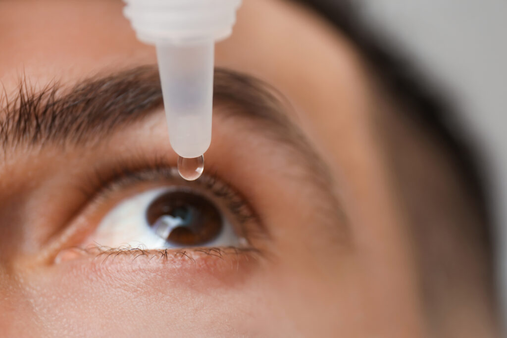 Imagen cercana de un hombre utilizando gotas para los ojos.