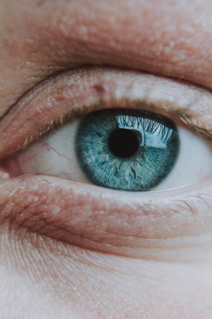 Close up vertical de una ojo color azul de una persona mayor con una pupila normal